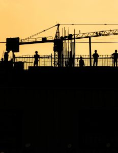 Construction workers silhouetted at sunset